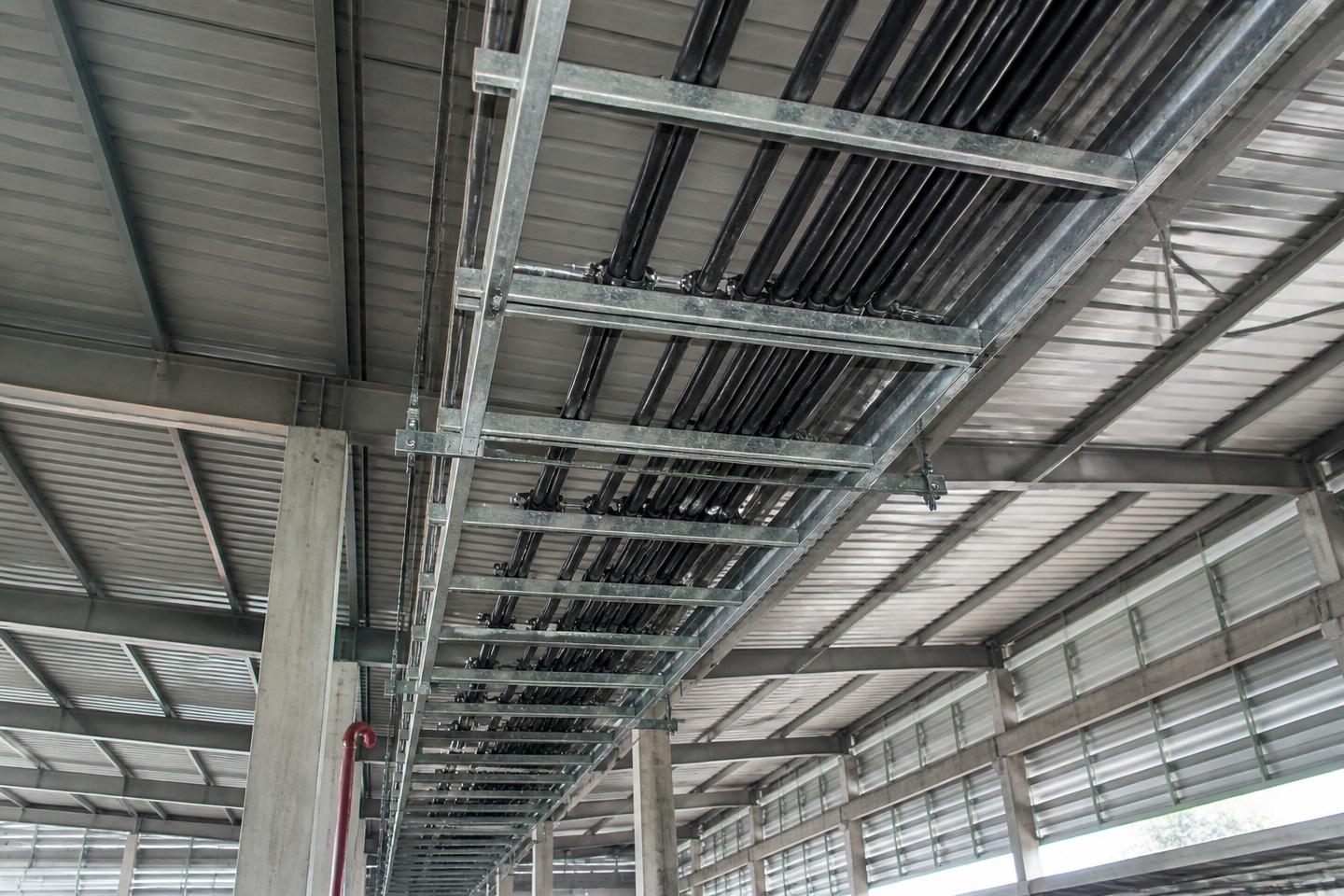 Generated representation of galvanized cable ladders routing industrial armoured cables beneath a Malaysian warehouse roof